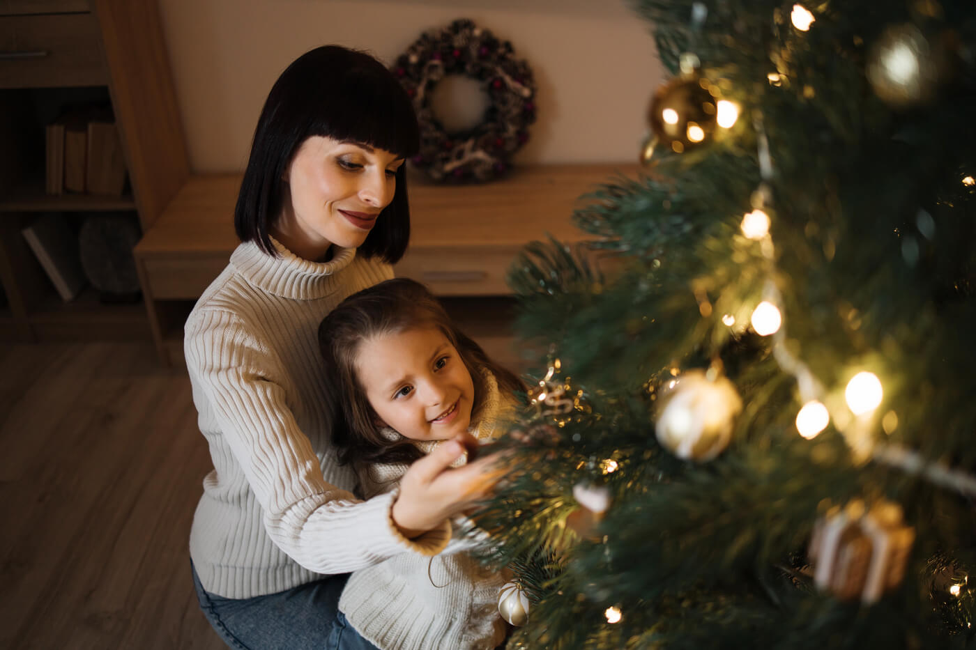 Mama a dcéra zdobia vianočný stromček v zlatej farbe